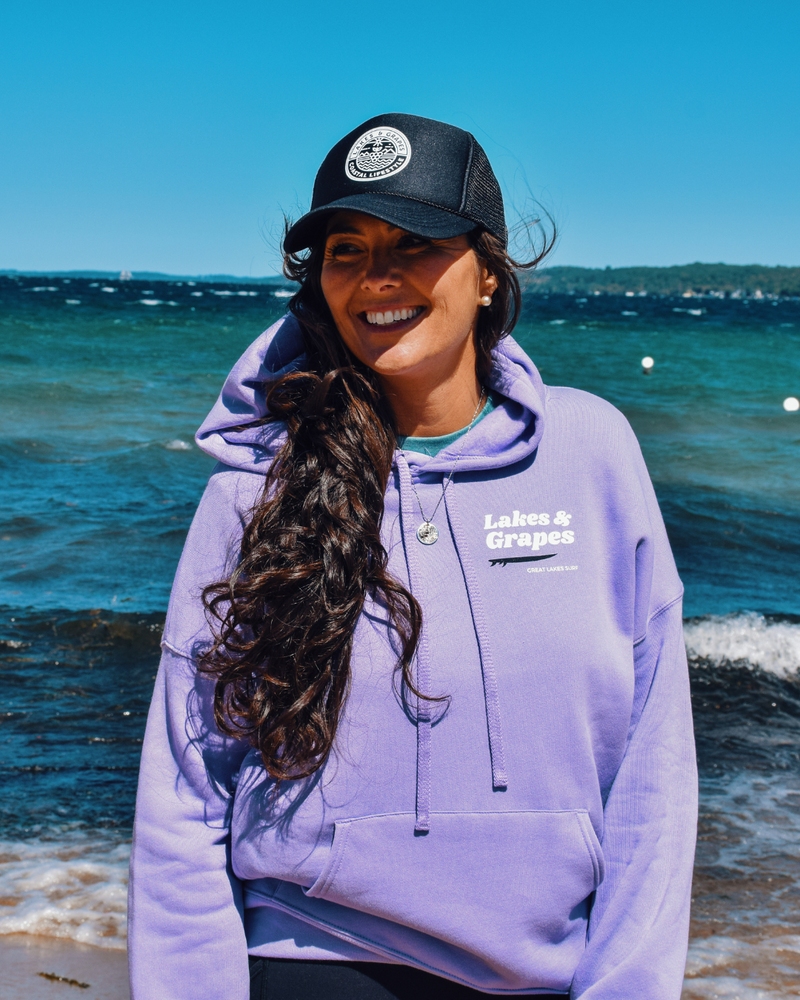 This image depicts the Lakes and Grapes Coastal Lifestyle Trucker Hat. The hat is a classic trucker style with a structured front panel and a gently curved brim. It's a versatile and fashionable accessory suitable for outdoor activities and coastal enthusiasts.