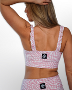 The image features a Pink Wave Ruffle Strap Sports Bra. The bra is designed with ruffle straps, providing a playful and feminine detail. It offers the necessary support for physical activities and workouts, ensuring comfort and ease of movement.