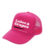 In this image, we see a Lakes and Grapes Hot Pink Great Lakes Surf Trucker Hat. Experience comfort and style as you embrace the spirit of the Great Lakes.