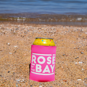
            
                Load image into Gallery viewer, Pink Rosé by the Bay Koozie keeping your drinks cold in the Traverse City beach sand by the lake
            
        