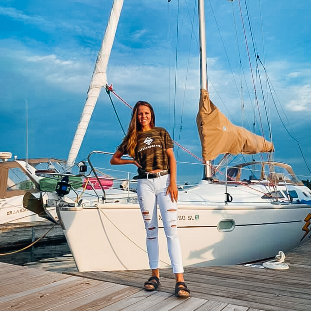 
            
                Load image into Gallery viewer, Wear the Lakes and Grapes Women&amp;#39;s Classic Camo Crop Tee on your next boat day or sailing adventure 
            
        